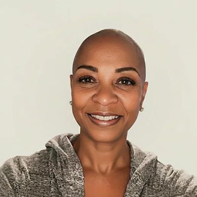Smiling woman with a shaved head and casual wear.