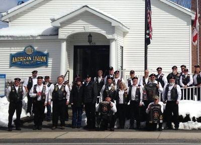 Group of veterans standing outside American Legion building in winter.