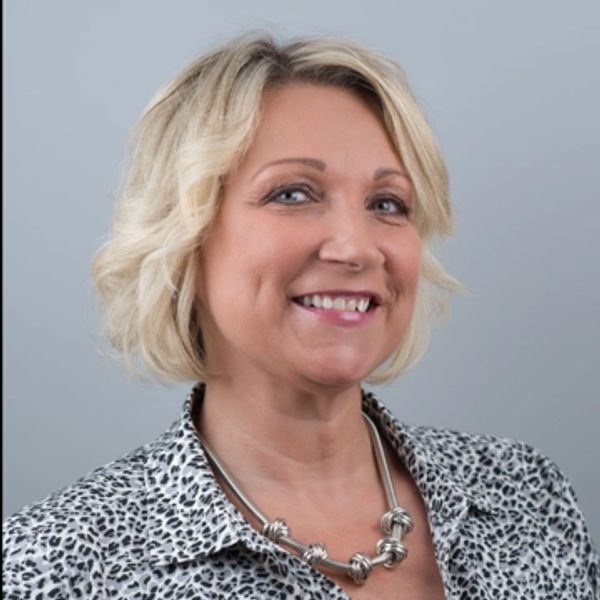 A person smiling and wearing a printed blouse