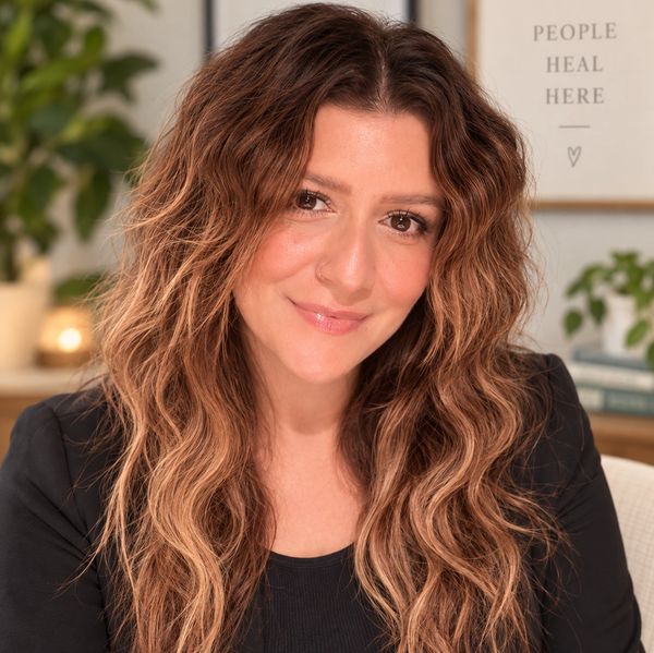 Smiling woman with long wavy hair and a nose ring.