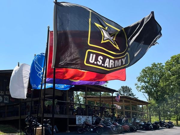 Military flags flying in front of SwitchBack Bar with motorcycles in front of outdoor deck