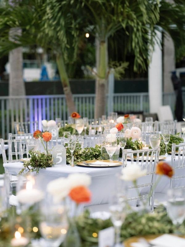Elegant outdoor wedding tables decorated with flowers and greenery.