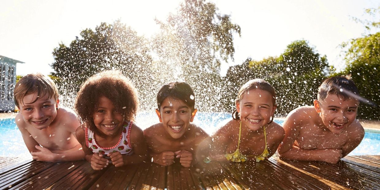 Photo of 5 kids splashing in a pool at summer camp