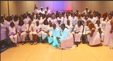 Large group of people dressed in white posing indoors.