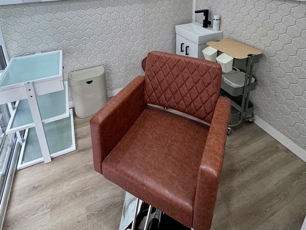 A modern salon chair in a minimalist, well-lit corner room.