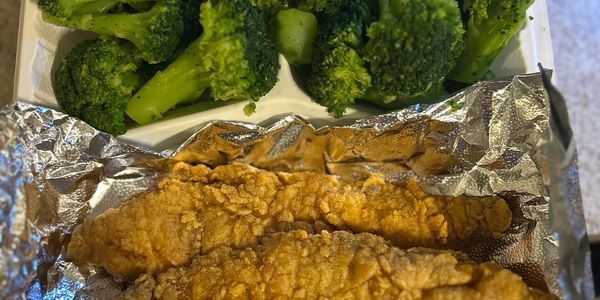 Fried chicken tenders with steamed broccoli in a divided container.