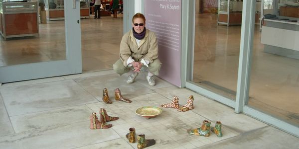 Portrait shot of Mary K Seyfarth behind some clay statues