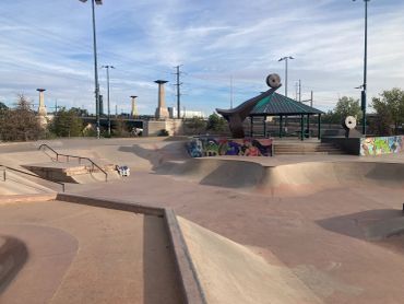 Empty skate park under a partly cloudy sky.
