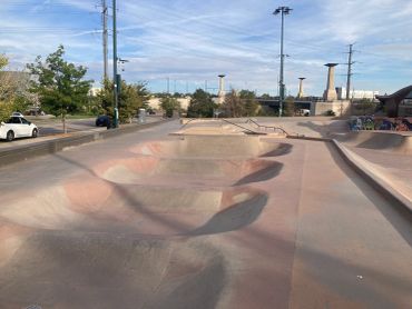 Empty concrete skatepark under blue sky.