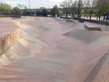 Empty urban skatepark with graffiti on the ramp.
