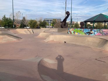Empty skatepark under a partly cloudy sky.