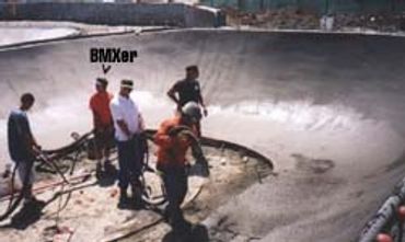 Group watching BMXer skate in empty pool.