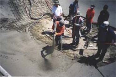 Workers pouring and leveling wet concrete.