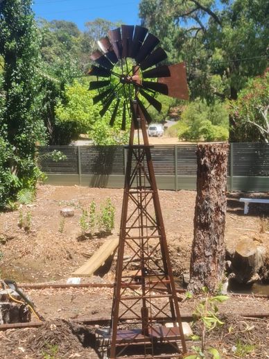 Rusty metal windmill in a garden.