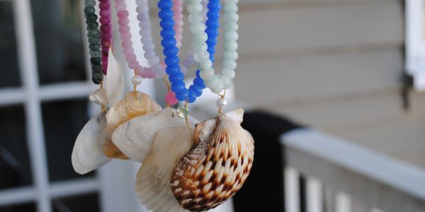 Colorful beaded necklaces with various seashell pendants hanging in a row.
