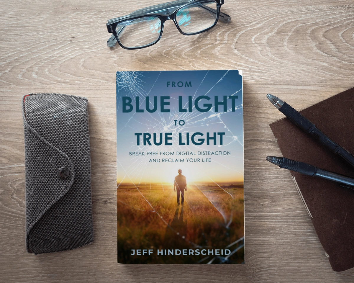 Book titled 'From Blue Light to True Light' by Jeff Hinderscheid on a wooden desk.