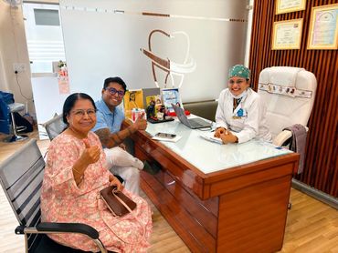 Two patients and a smiling female dentist in a dental clinic office.