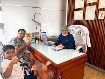 Dentist and patient with child showing thumbs up in clinic.