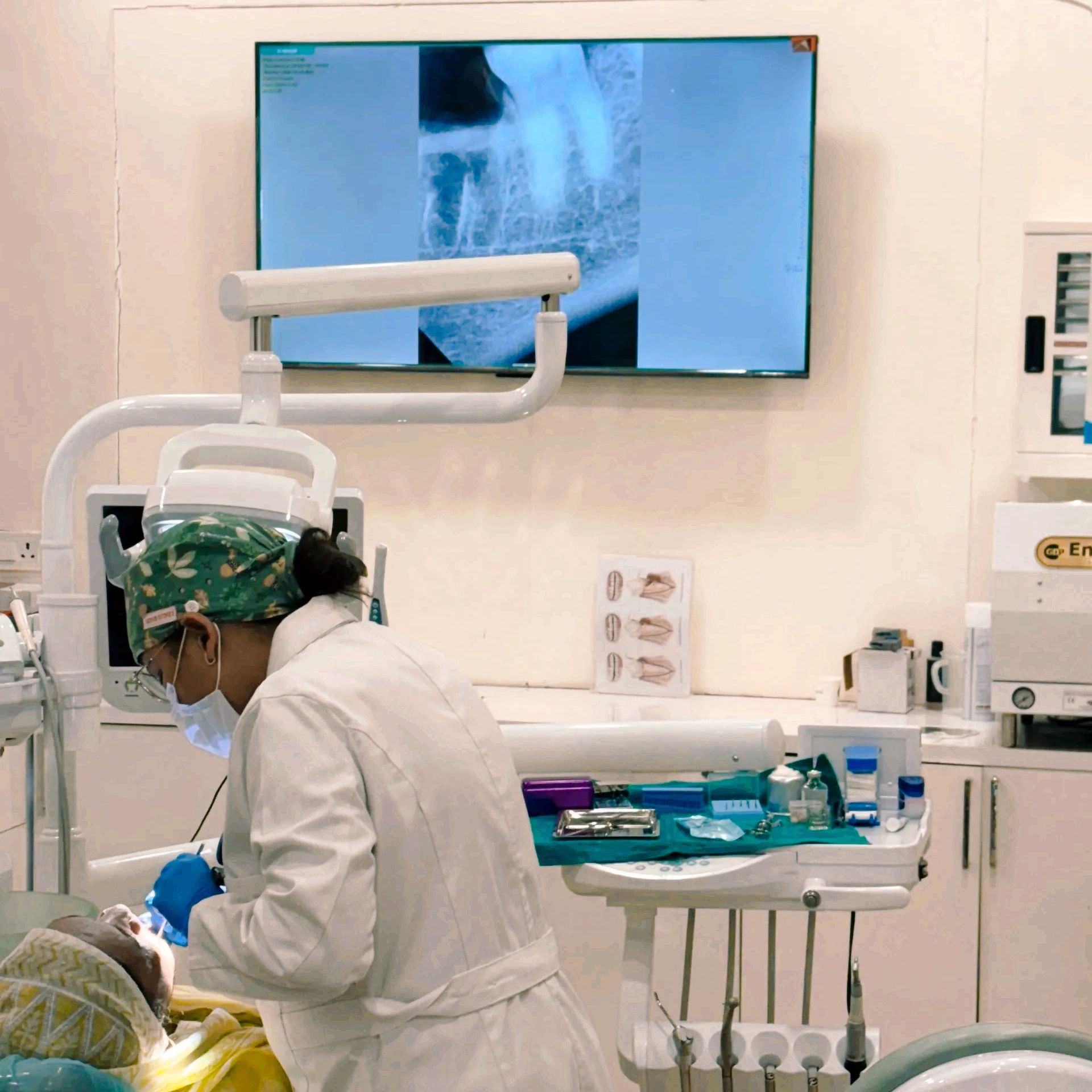 Dentist treating a patient with a dental x-ray displayed.