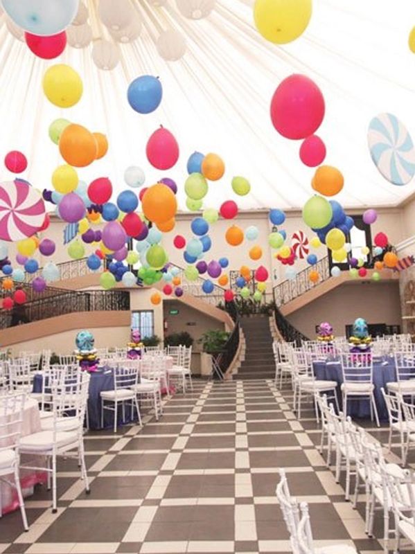 Colorful balloons decorate a large banquet hall.