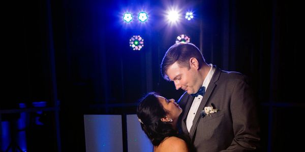 A couple shares a romantic moment on the dance floor under colorful lights.