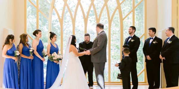 A couple exchanging vows during a wedding ceremony with bridal party and groom party.