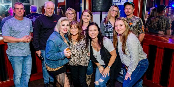 Group of friends posing happily inside a bar during karaoke.