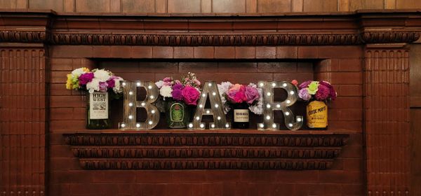 Decorative BAR sign with flowers on a brick mantel.