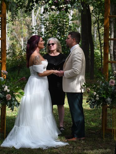 Couple exchanging vows outdoors with officiant during wedding ceremony.