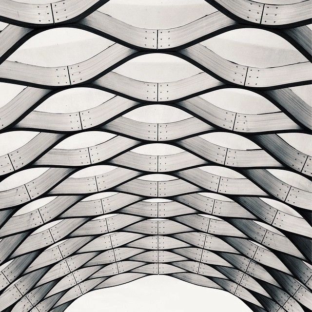 Curved wooden beams form a repetitive, wave-like architectural pattern.