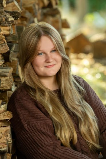 Young woman with long blonde hair smiling outdoors.