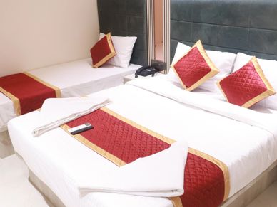Neatly arranged hotel room with a double bed and single bed, decorated with red and gold accents.