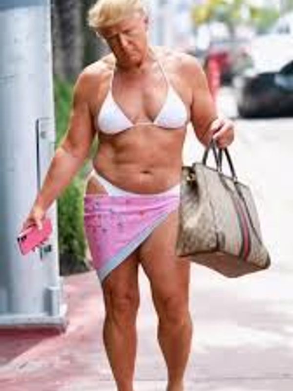 A person in a white bikini and pink sarong walking with a large handbag.