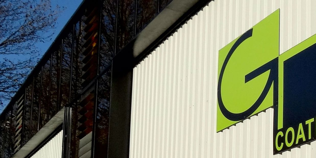 Close-up of a building's exterior with a green and black logo on a white wall.