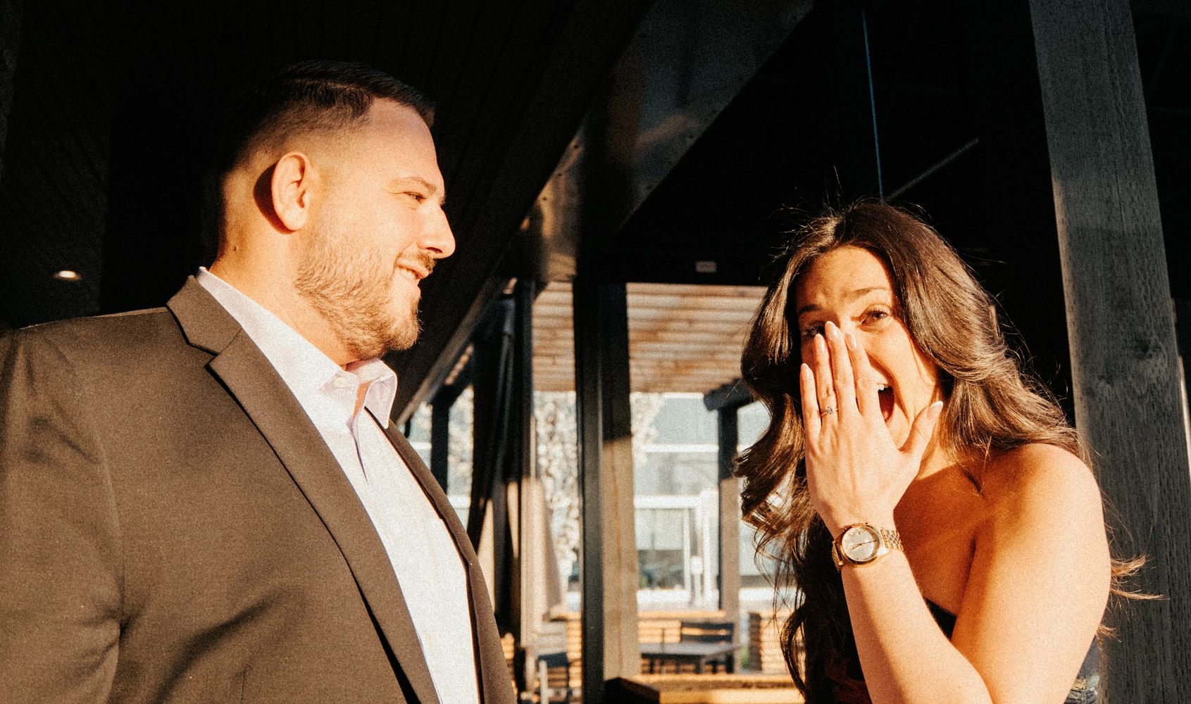 Man smiling at woman showing surprise and engagement ring.