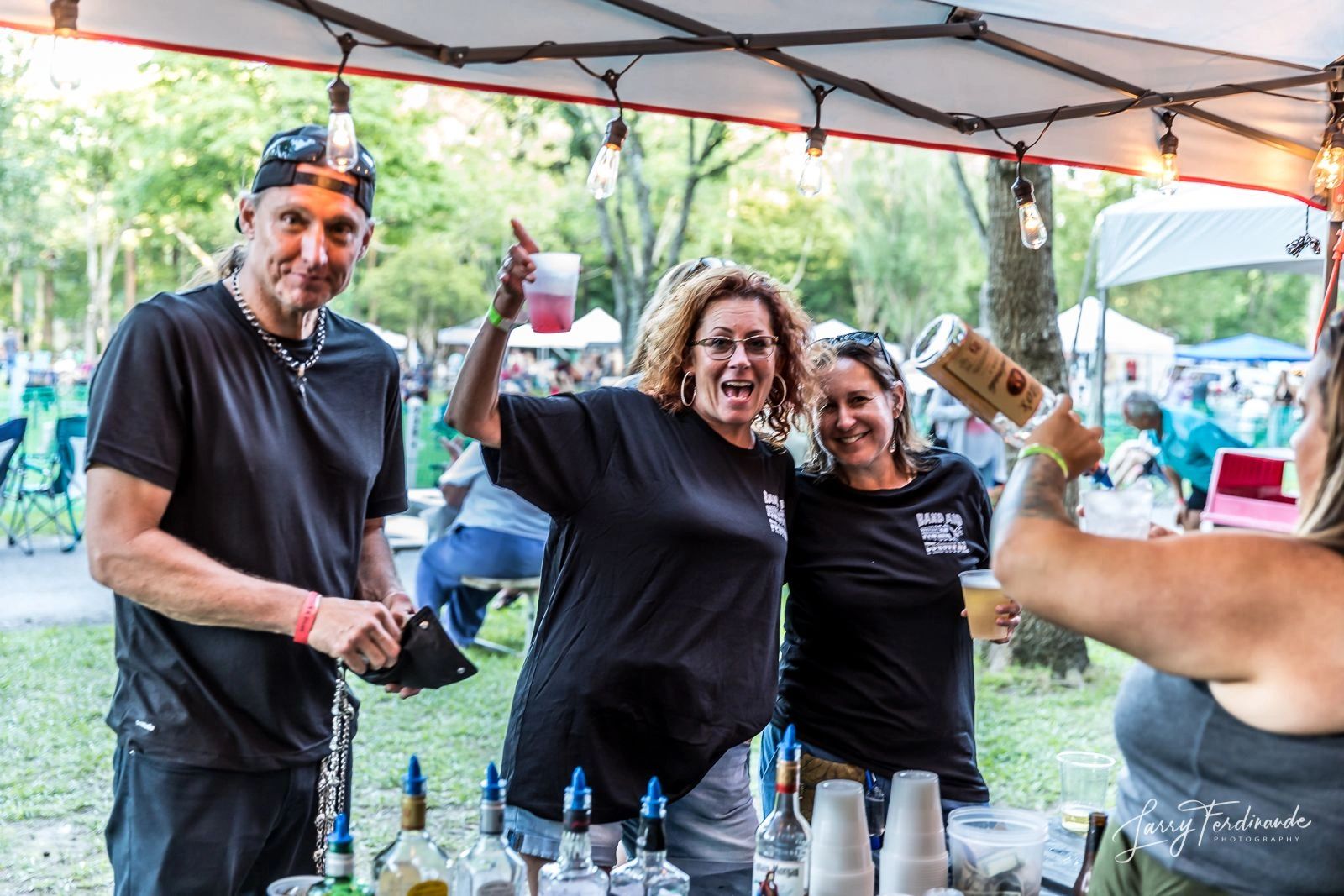 Group enjoying drinks at outdoor event under tent lights.