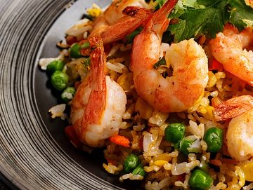 Shrimp fried rice with peas and vegetables on a decorative plate.