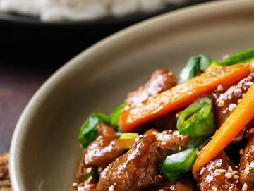 Close-up of stir-fried beef with carrots and green onions.