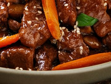 Close-up of stir-fried beef with carrots and green onions.