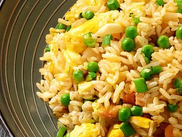 A close-up of fried rice with peas and scrambled eggs on a plate.