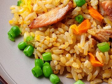 Close-up of fried rice with peas, carrots, and pieces of meat.