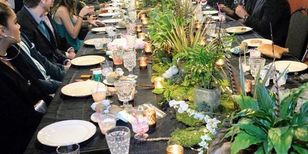 Elegant dinner party with lush greenery centerpiece and candles.