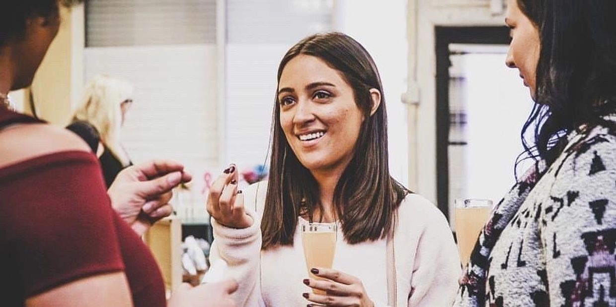 Three women chatting and enjoying drinks at a social gathering.