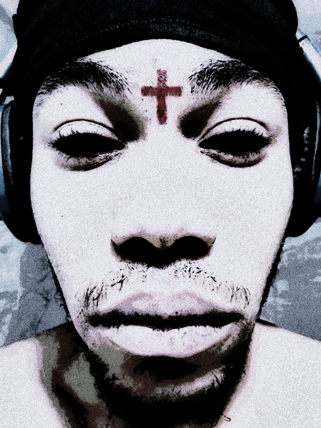 Close-up of a person with a red cross on their forehead and eyes digitally altered to black.