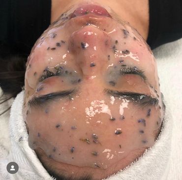 Person with a clear gel facial mask containing black seeds applied on their face.