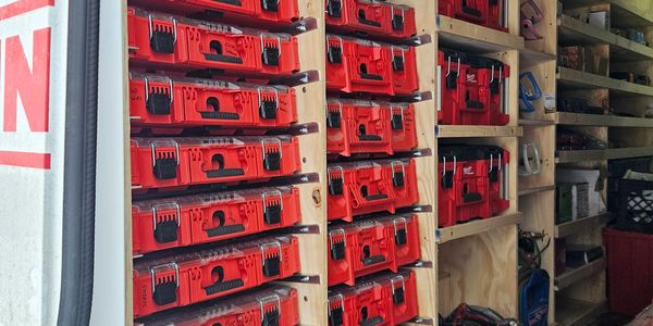 Storage shelves filled with organized red toolboxes.