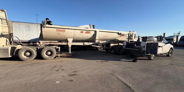 Waco Road Service truck providing roadside assistance to a truck and trailer at a truck stop in Waco