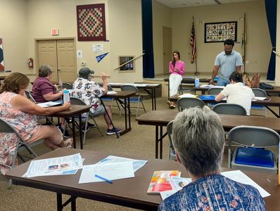 A community meeting with people listening and discussing in a room.