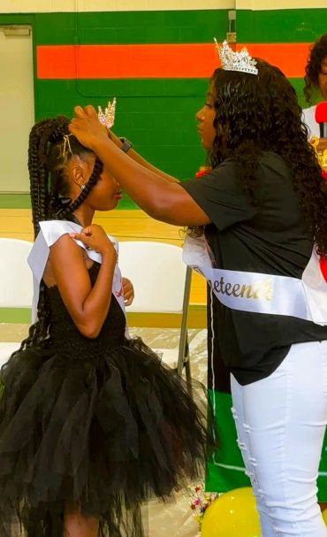 Woman crowns young girl in a pageant.