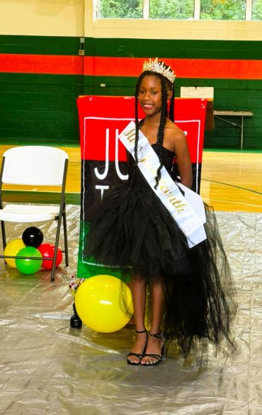 Young girl crowned with sash and crown at event.